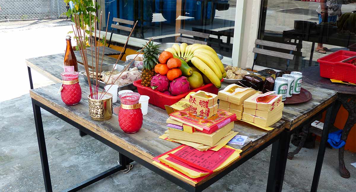 Offering table for the Ghost Festival in China, filled with food and Joss Papers.